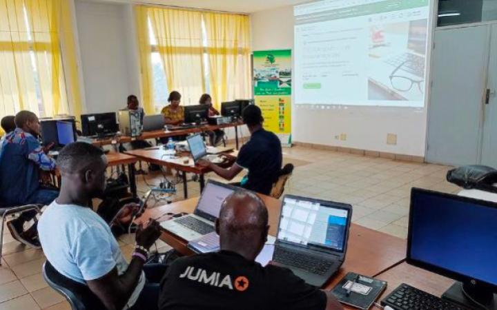 Participants travaillant sur des ordinateurs dans une salle de formation, face à un écran de projection.