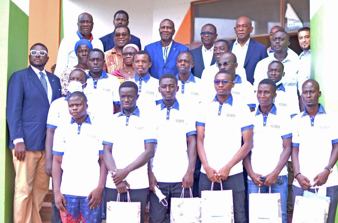Photo de groupe de jeunes en polo blanc, entourés de responsables, devant un bâtiment.