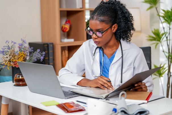Photographie : une médecin consultant un dossier devant son ordinateur portable